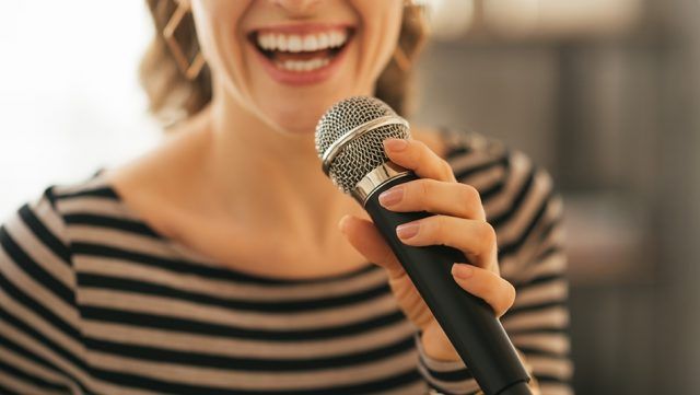 Closeup on young woman singing with microphone in loft apartment